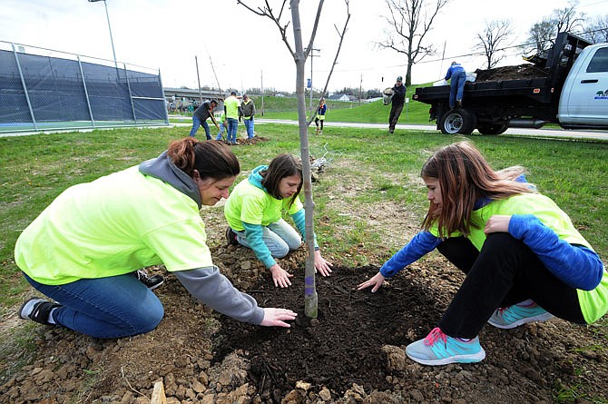 April Hager is assisted by daughters Matti, 9, and Kristi, 11, Saturday, April 21, 2018, during Serve Jeff City. The family planted a tree at the Myrtle Smith Livingston Park tennis courts. The annual citywide day of service started in 2012 with volunteers helping at sites across the community.