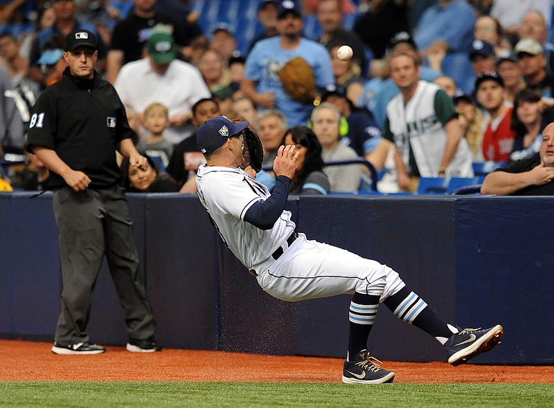 Umpire Quinn Wolcott, left, watches as Tampa Bay Rays first baseman Brad Miller misses a pop fly in foul territory hit by Minnesota Twins' Robbie Grossman during the first inning of a baseball game Saturday, April 21, 2018, in St. Petersburg, Fla. (AP Photo/Steve Nesius)