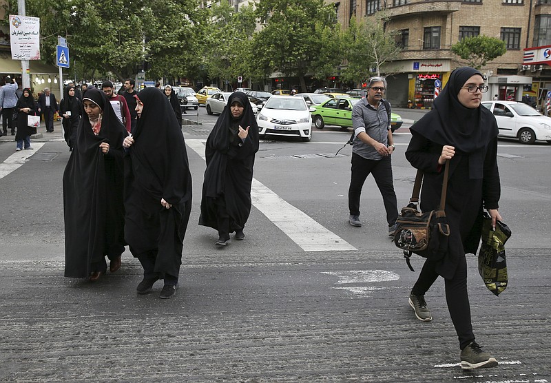In this Sunday, April 22, 2018, photo, pedestrians cross a street in Tehran, Iran. A grainy video of female officers from Iran’s morality police assaulting a young woman whose headscarf only loosely covered her hair has sparked a new public debate on the decades-long requirement for women in the Islamic Republic. (AP Photo/Vahid Salemi)