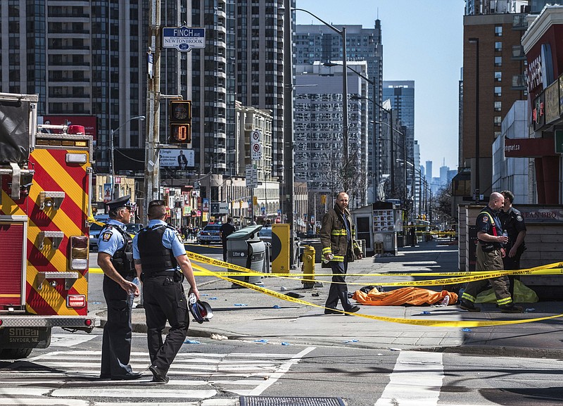 A body lies covered on the sidewalk in Toronto after a van mounted a sidewalk crashing into a number of pedestrians on Monday, April 23, 2018.A van apparently jumped a curb Monday in a busy intersection in Toronto and struck numerous people and fled the scene before it was found and the driver was taken into custody, Canadian police said.  (Aaron Vincent Elkaim/The Canadian Press via AP)