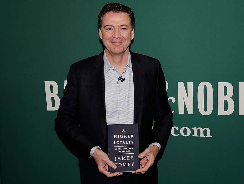 FILE - In this April 18, 2018 file photo, former FBI director James Comey poses with his book "A Higher Loyalty" at a Barnes & Noble book store in New York. Flatiron Books announced Tuesday that sales topped 600,000 copies, a number that includes print, audio and e-books. The former FBI director’s memoir has been one of the year’s most anticipated releases. (AP Photo/Frank Franklin II, File)