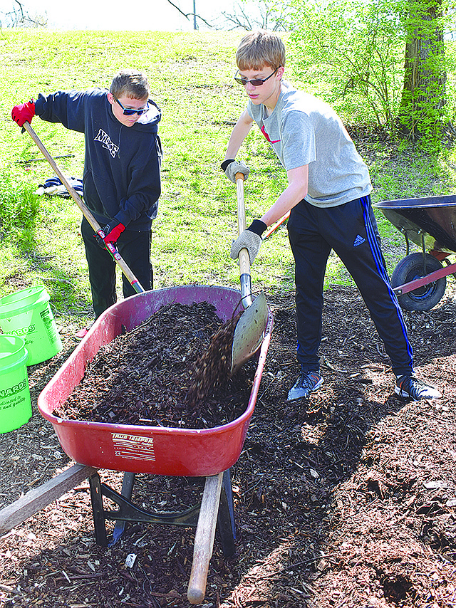 Sam Uptergrove, left, and Luke Louraine of First United Methodist Church load mulch into a wheelbarrow Sunday to be put onto a trail at McClung Park. They were working on one of several dozen projects as a part of Mission JC.