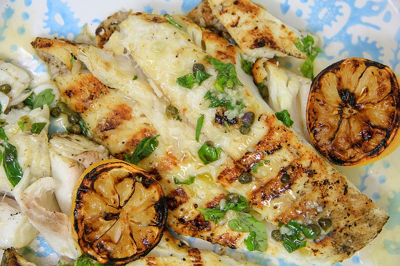 This April 20, 2018 photo shows grilled halibut with butter caper herb sauce in Bethesda, Md. This dish is from a recipe by Melissa d'Arabian.  (Melissa d'Arabian via AP)