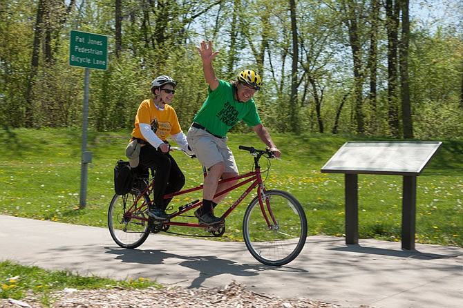 Charles Skornia waves from the front seat of the tandem bicycle he rode with his wife, Charlotte Skornia, on Monday, April 30, 2018, during Bicycle, Pedestrian and Trails Day. Riders, including a few state lawmakers, biked from the Governor's Garden across the pedestrian/bicycle path and onto the Katy Trail. The event aimed to promote the expansion of bicycle- and pedestrian-friendly roadways and nature trails. 