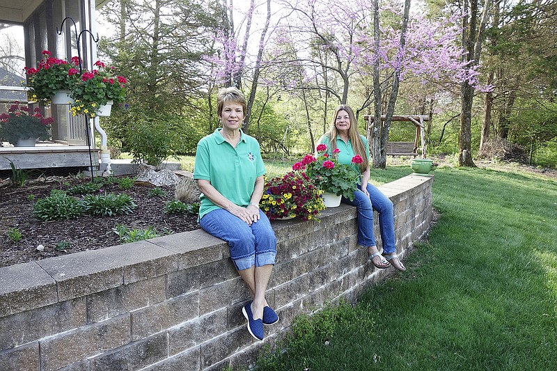 Fulton Garden Club members Melody Clark (left) and Diane Wilfley Branch have been preparing for the club's annual plant sale, which will be Saturday morning at the Fulton Farmers Market. Hanging baskets are just some of the offerings.