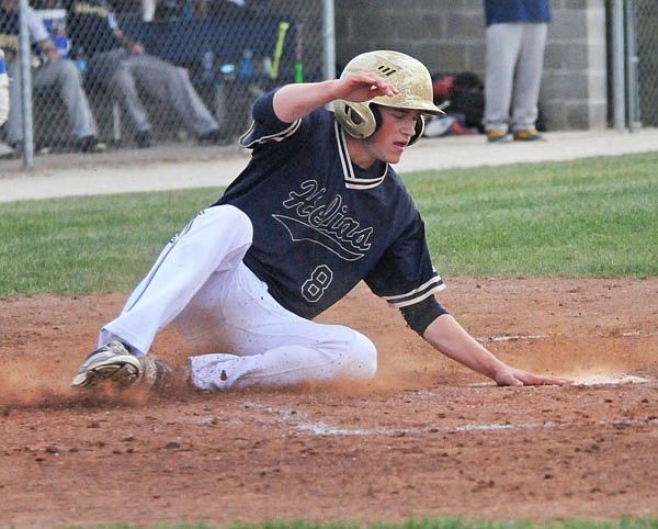 Zach Woehr of Helias reaches out to touch home plate for a run scored during Wednesday's game against Battle at the American Legion Post 5 Sports Complex.