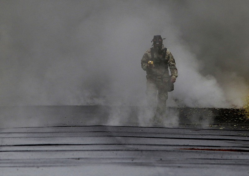 First Lt. Aaron Hew Len, of the U.S. National Guard, tests air quality near cracks that are emitting toxic gasses from a lava flow in the Leilani Estates subdivision near Pahoa, Hawaii, Tuesday, May 8, 2018. Scientists confirm that volcanic activity has paused at all 12 fissures that opened up in a Hawaii community and oozed lava that burned 35 structures. Officials warn that hazardous fumes continue to be released from the cracks in the ground. (AP Photo/Caleb Jones)