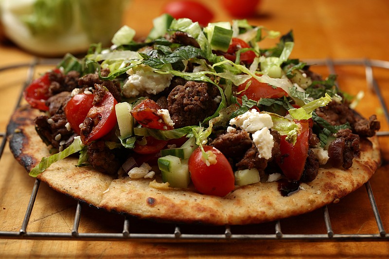 Grilled pitas are the foundation for an open face sandwich piled with ground lamb, fresh tomatoes, chopped cucumbers and crumbled feta, all garnished with za'atar and sumac. (E. Jason Wambsgans/Chicago Tribune/TNS)