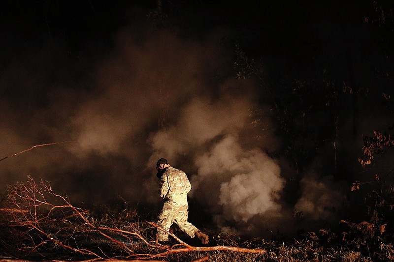 Sgt. 1st Class Carl Satterwaite, of the U.S. National Guard, tests air quality near cracks emitting volcanic gases from a lava flow in the Leilani Estates subdivision near Pahoa, Hawaii Thursday, May 10, 2018. Kilauea has destroyed more than 35 structures since it began releasing lava from vents about 25 miles (40 kilometers) east of the summit crater. (AP Photo/Jae C. Hong)