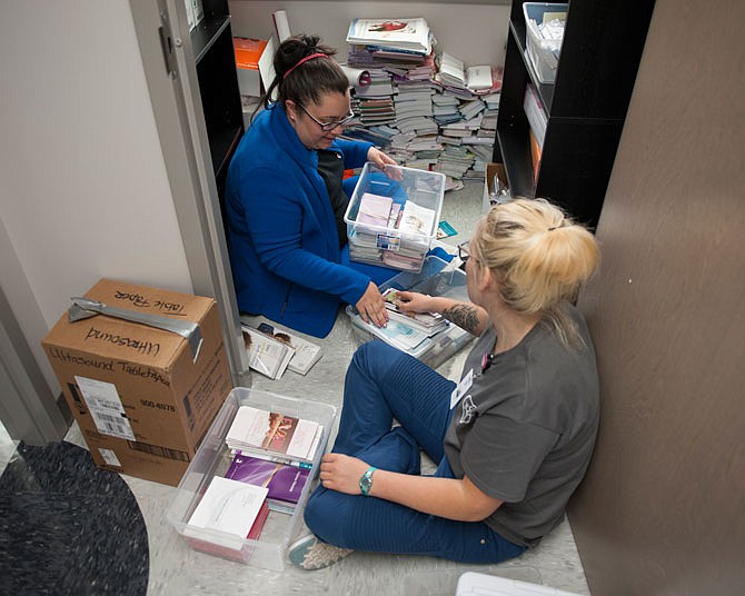 Lacey Jennings, top, and Kayla Imhoff sort through informational pamphlets Friday in the new Community Health Center of Central Missouri building, located at 1511 Christy Drive.