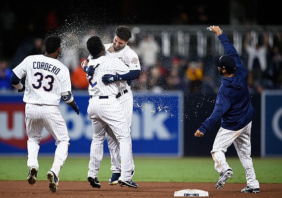 Eric Hosmer (center right) celebrates with Padres teammate Jose Pirela after driving in the winning run with a double as Franchy Cordero (left) joins in during the 13th inning of Saturday night's game against the Cardinals in San Diego. The Padres won 2-1.