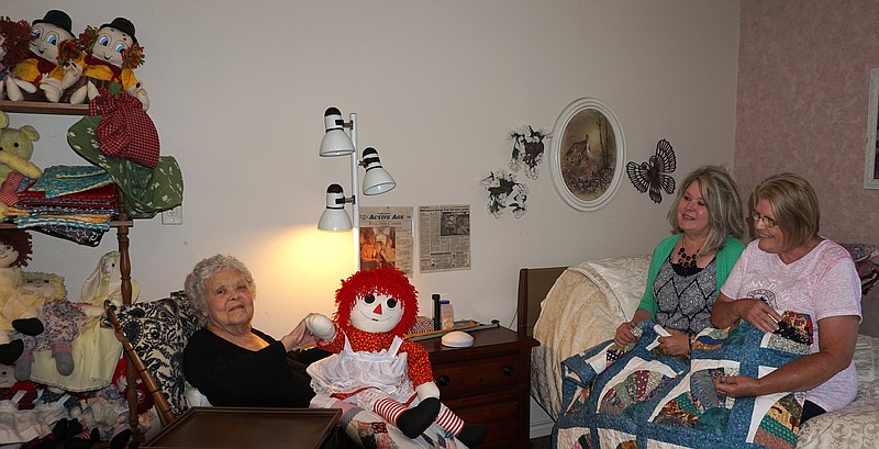 Arene Patten's assisted living room is filled with the 92-year-old's creations—dolls. She's holding a favorite. With her are, from left, daughter Kathy Endsley and friend Linda Ward.
