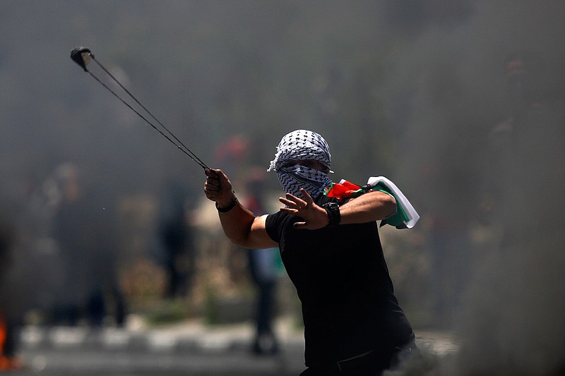 A Palestinian protester hurls a stone during clashes with Israeli forces after a rally to mark the 70th anniversary of what Palestinians call their "nakba," or catastrophe — the uprooting of hundreds of thousands in the Mideast war over Israel's 1948 creation, in the West Bank city of Bethlehem, Tuesday, May 15, 2018. (AP Photo/Majdi Mohammed)