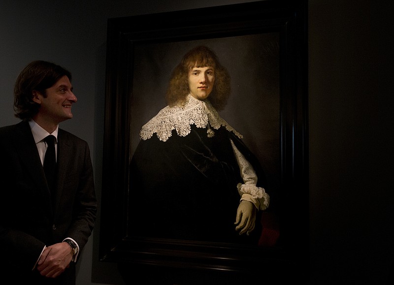 Jan Six poses Wednesday, May 16, 2018, with a painting attributed to famous Dutch Master Rembrandt after it was put on display at the Hermitage museum in Amsterdam, Netherlands.