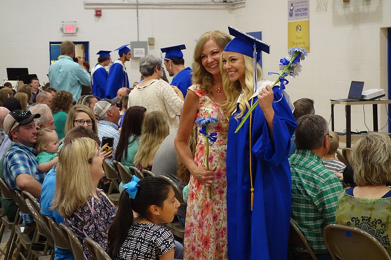 <p>Allen Fennewald/News Tribune</p><p>Emily Strein gives her mother, Tammie Strein, a gerbera daisy Friday during the Jamestown graduation ceremony.</p>