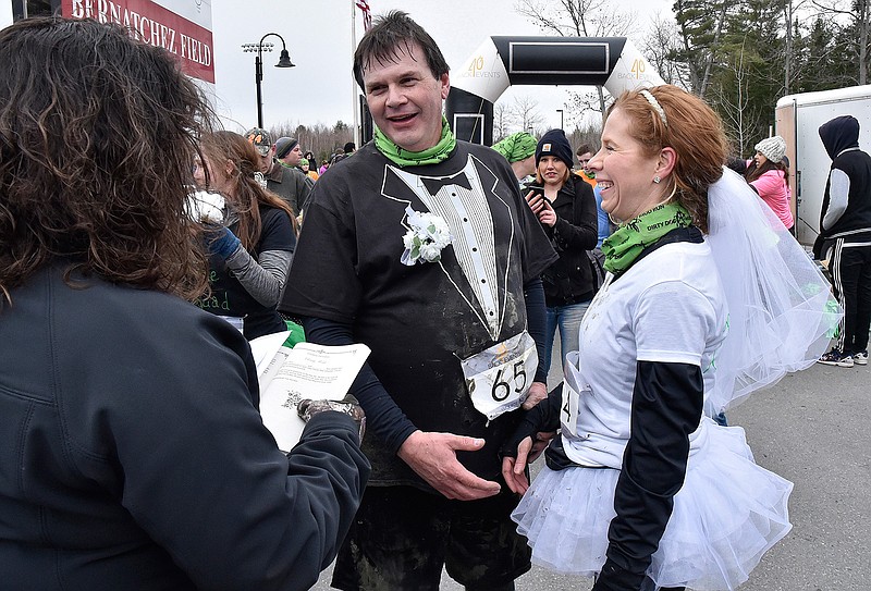 In this Sunday, April 15, 2018 photo, wet and muddy Bill Jackson and Jennifer Denis, both of Randolph, Maine, exchanged wedding vows before friends and justice of the peace Renee Longley after running in the Thomas College Dirty Dog Mud run in Waterville, Maine. (David Leaming/The Central Maine Morning Sentinel via AP)
