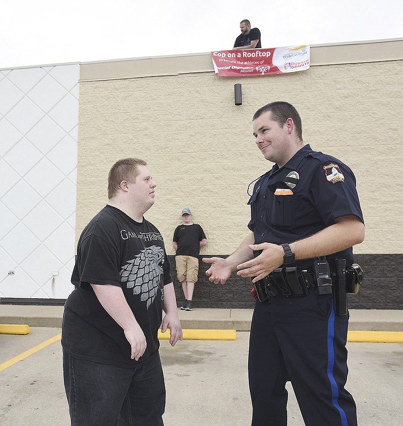 Jefferson City police officer Adam Lueckenhoff talks sports with Tony Crockett who stopped at Dunkin' Donuts on Friday morning with his mom, Rheya Meyners, and her husband, Nathanael Meyners. Lueckenhoff was on the ground to accept donations as he assisted Adam Koestner, atop the building, with fundraising for Special Olympics. 