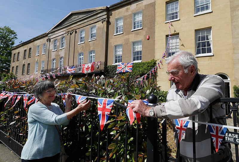 Local residents hang flags to decorate their house Friday along the route that the carriage carrying Prince Harry and Meghan Markle will take after their marriage in Windsor, England.