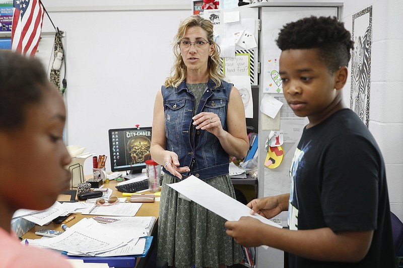In this Monday, May 14, 2018 photo photo, Tanya Thomas, center, helps her students with classwork at Slate Ridge Elementary School, Monday, May 14, 2018, in Reynoldsburg, Ohio. Thomas is donating a kidney to save the life of Eva Evans, a student at her school. (AP Photo/John Minchillo)