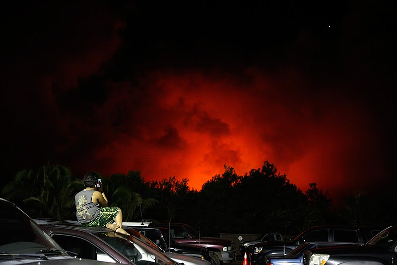 A young boy photographs the sky turned red from lava flows in the Leilani Estates subdivision near Pahoa, Hawaii Friday, May 18, 2018. Hawaii residents covered their faces with masks after a volcano menacing the Big Island for weeks exploded, sending a mixture of pulverized rock, glass and crystal into the air in its strongest eruption of sandlike ash in days. (AP Photo/Jae C. Hong)