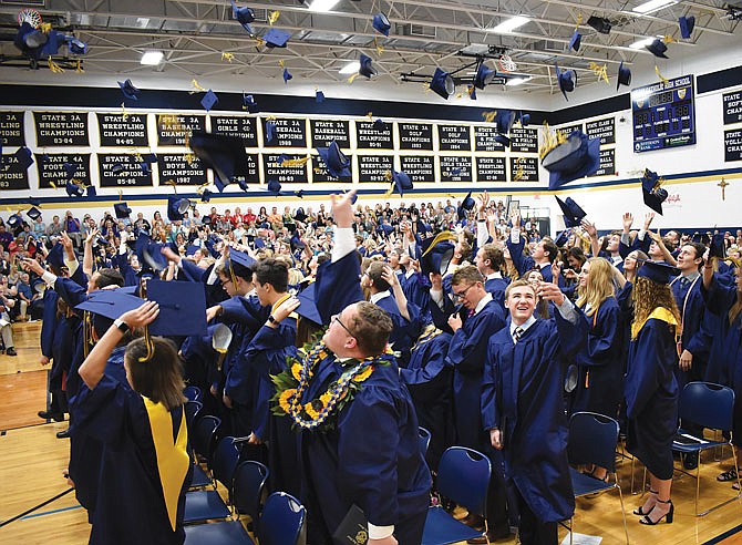 Helias Catholic High School graduating seniors toss their caps in the air at the end of Sunday's graduation ceremonies.