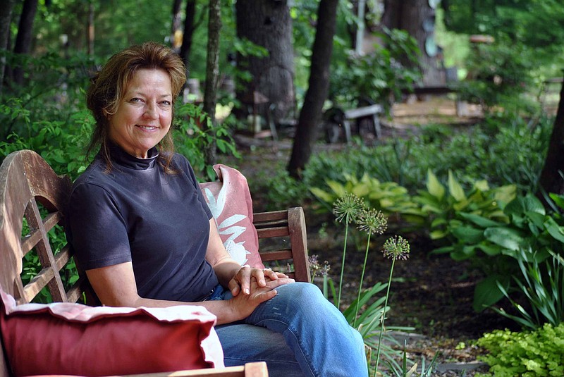 Mary Callahan sits on a bench along a path that leads to a wooded retreat area complete with vintage accents and a porch swing, one of her favorites spots in her home gardens, which won the Bittersweet Garden Club's May 2018 Garden of the Month. 
