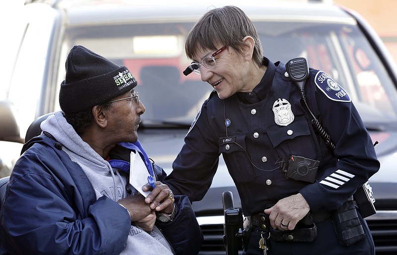 FILE - In this March 12, 2015, file photo, Seattle police officer Debra Pelich, right, wears a video camera on her eyeglasses as she talks with Alex Legesse before a small community gathering in Seattle. While the Seattle Police Department bars officers from using real-time facial recognition in body camera video, privacy activists are concerned that a proliferation of the technology could turn the cameras into tools of mass surveillance. The ACLU and other organizations on Tuesday, May 22, 2018, asked Amazon to stop selling its facial-recognition tool, called Rekognition, to law enforcement agencies. (AP Photo/Elaine Thompson, File)