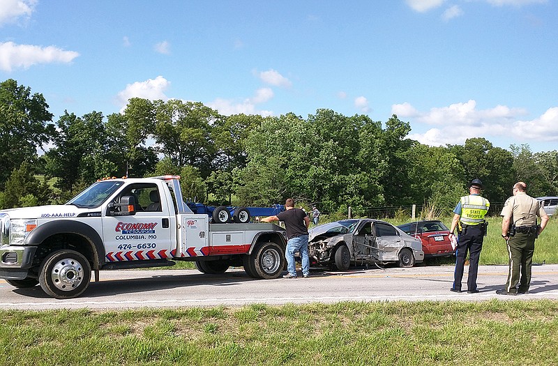 Lt. Curtis Hall, right, of the Callaway County Sheriff's Office and a Missouri Highway Patrol trooper look on while mangled vehicles are towed away from one of three crash sites along Route F in Callaway County on Monday, May 21, 2018.