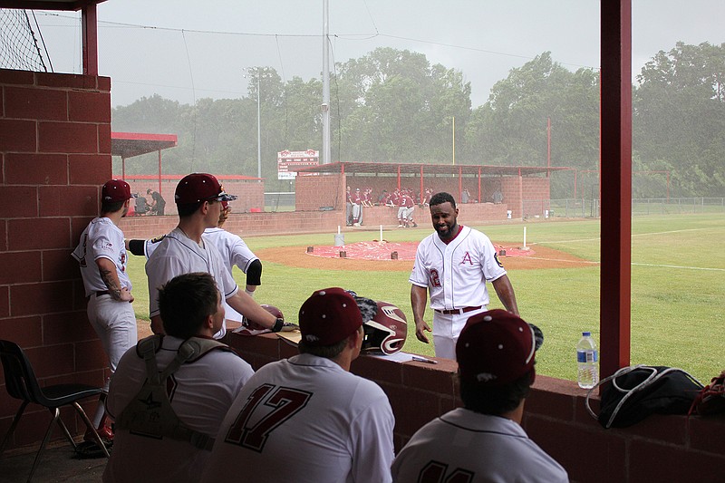 Texarkana Razorbacks manager Carlton Bailey talks to some of his players as the Hogs and Junior Hogs, far dugout, wait out a rain delay that postponed both of the teams' season openers Tuesday at Arkansas High School.