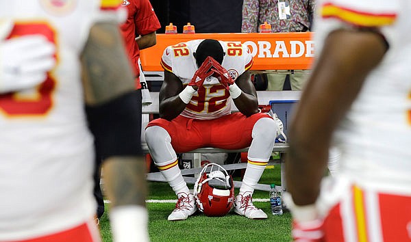 In this Oct. 8, 2017, file photo, Chiefs linebacker Tanoh Kpassagnon sits on the bench during the national anthem before a game against the Texans in Houston. NFL owners have approved a new policy aimed at addressing the firestorm about national anthem protests, permitting players to stay in the locker room during the "The Star-Spangled Banner", but requiring them to stand if they come to the field.