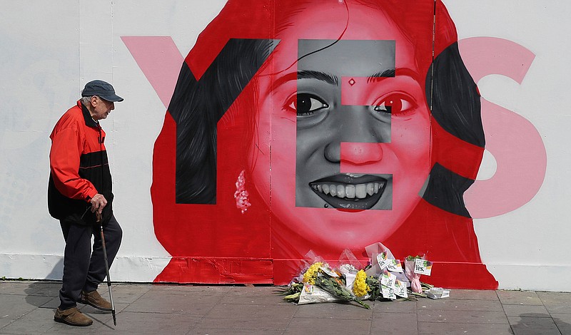 A man walks Friday, May 25, 2018, past a mural showing Savita Halappanavar, a 31-year-old Indian dentist who had sought and been denied an abortion before she died after a miscarriage in a Galway hospital, with the word YES over it, in Dublin, Ireland, the day of a referendum on the 8th Amendment of the Irish Constitution. (Photo by Niall Carson/PA via AP)