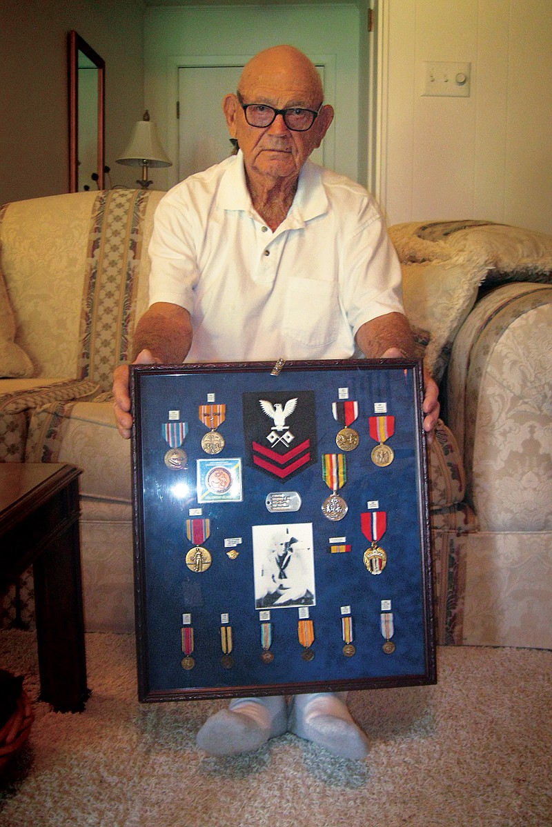 Texarkana, Texas, native George H. Ponder poses for a photograph with medals and other memorabilia earned during World War II. Ponder, 91, served as a Navy signalman 2nd class in Pacific. He was aboard the USS John Penn when a Japanese torpedo plane "swooped down and dropped its torpedo," which sank the warship in about 19 minutes.