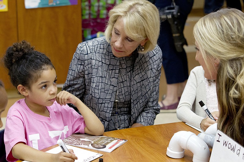 Education Secretary Betsy DeVos accompanied by first grade teacher Alexandra Lyons speaks to student Ayana Greene, during a visit of the Federal School Safety Commission at Hebron Harman Elementary School in Hanover, Md., Thursday, May 31, 2018. DeVos listened to first-graders share stories about friendship during a field trip by a presidential commission seeking ways to stem a steady stream of school violence. The school specializes in mentoring and counseling as opposed to punitive discipline. (AP Photo/Jose Luis Magana)
