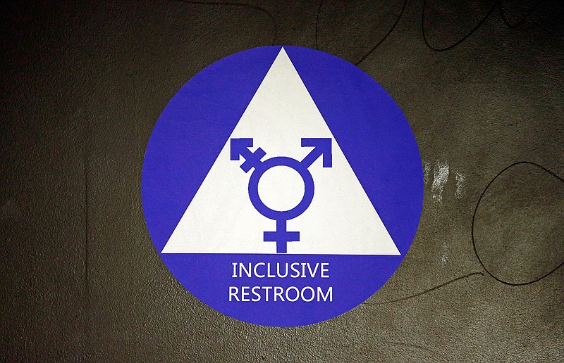 A new sticker designates a gender-neutral bathroom May 17, 2016, at Nathan Hale High School in Seattle. On college campuses and in workplaces, across social media and in deference to nonbinary people, gender-neutral pronouns are more than just a new wave of political correctness. Pronouns "they" and "them" seem to be winning the race of acceptance as gender neutrals. (AP Photo/Elaine Thompson)