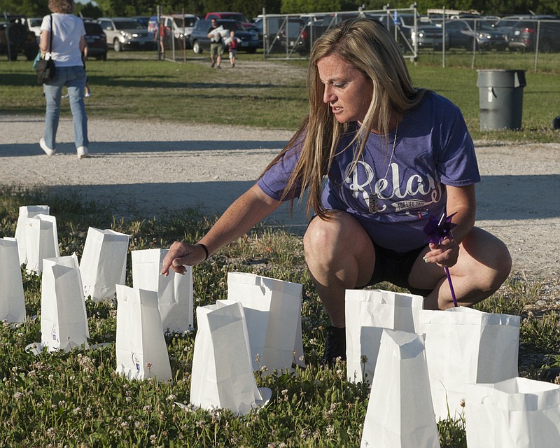 
Nicole Caviness places a luminary with others lining the inside of the walking track during Relay For Life at the Jefferson City Jaycee Fairgrounds on Friday, June, 2018. The luminaries were placed in memory of a loved one touched by cancer.