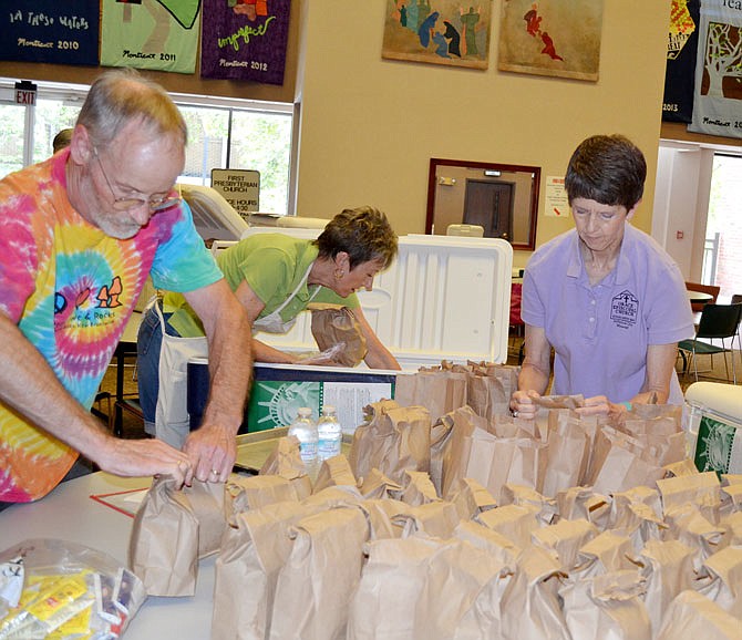 Volunteers Ken Lubbering, left, Paula Hartsfield, and Karel Lowery work in Jefferson City in 2017 to fill sack lunches for the summer children's food program with The Food Bank of Central and Northeast Missouri.