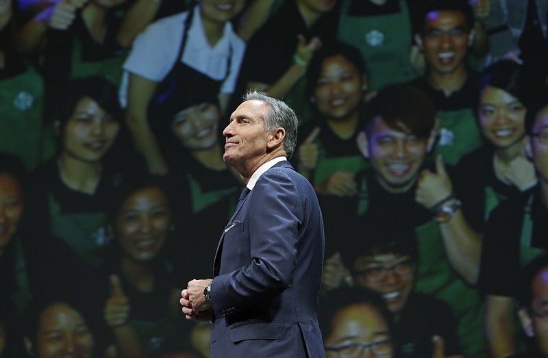 FILE - In this March 23, 2016, file photo, Starbucks CEO Howard Schultz walks in front of a photo of Starbucks baristas, at the coffee company's annual shareholders meeting in Seattle. Starbucks Corp. says Schultz is stepping down executive chairman later this month. Schultz, who oversaw the transformation of Starbucks into a global chain with more than 28,000 locations, had retired as CEO last year to focus on innovation and social impact projects as executive chairman. (AP Photo/Ted S. Warren, File)