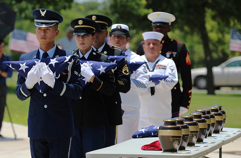 Military service members with the Armed Services Honor Guard prepare to present folded flags Friday, June 1, 2018, as Fort Sam Houston National Cemetery and the Missing In America Project conduct a military burial service for the cremated remains of eight unclaimed U.S. military veterans in San Antonio. The remains, which for years had been stored in the basement of a county courthouse in the Texas Panhandle, have been interred as part of a formal ceremony in San Antonio. (Kin Man Hui/The San Antonio Express-News via AP)