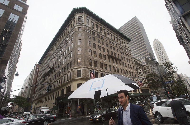 FILE- In this Oct. 24, 2017, file photo a man walks past the Lord & Taylor flagship store in New York. Lord & Taylor is abandoning plans to keep a store in the Fifth Avenue flagship it is selling, as the chain's owner closes more stores and focuses on online sales. The announcement Tuesday, June 5, 2018, comes about seven months after the company said it would sell the century-old building to office space sharing company WeWork (AP Photo/Mark Lennihan, File)