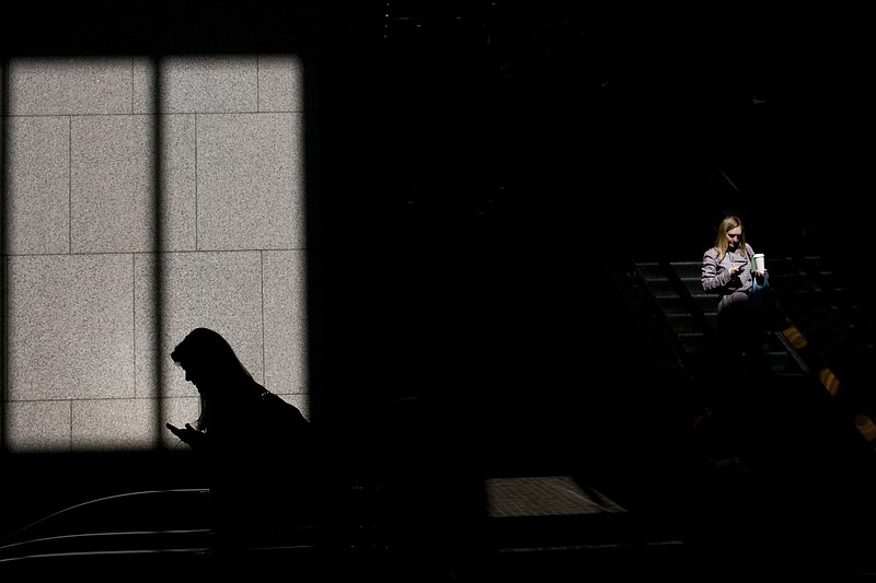 FILE- In this June 1, 2018, file photo, commuters look at their phones in Los Angeles. Technology giants like Facebook, Google and Amazon ask us to trust them with ever-more sensitive aspects of our lives, from our relationships to our private conversations. But there’s a catch: If they prove unworthy of that trust, the repercussions are scant and alternatives seem hard to find. (AP Photo/Jae C. Hong, File)