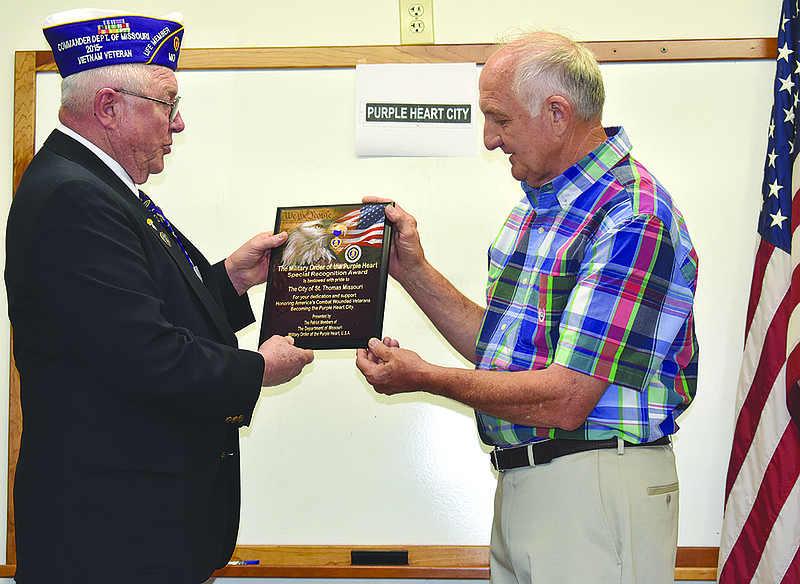 State Commander John Dismer, left, presents a plaque declaring St. Thomas as a Purple Heart City at a Sunday ceremony at the St. Thomas City Hall.