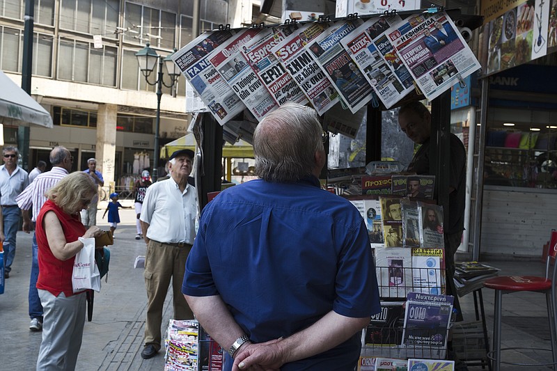 People read newspaper front pages a day after a Greek- Macedonian agreement, at a kiosk in Athens, on Wednesday, June 13, 2018. A historic deal ending a decades-long dispute between neighbors Greece and Macedonia over the latter's name met with mixed reactions in both countries Wednesday, with some welcoming the agreement and others horrified at what they see as unacceptable concessions. (AP Photo/Petros Giannakouris)