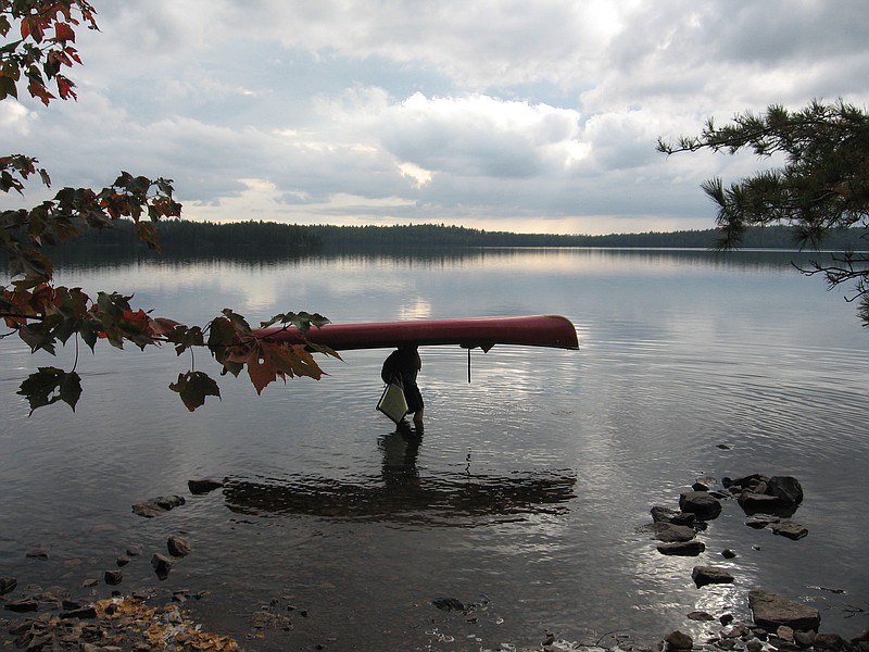 This Sept. 16, 2017 photo shows a visitor to Minnesota's Boundary Waters Canoe Area Wilderness getting ready to put the 16.5-foot canoe back in the water after carrying it overhead across a portage to Parent Lake. Hundreds of years ago, Native Americans and fur traders carved these trails through the forests connecting the more than one thousand lakes in the area. (Giovanna Dell'Orto via AP)