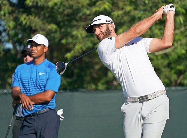 Dustin Johnson hits off the fourth tee as Tiger Woods looks on during Tuesday's practice round for the U.S. Open at Shinnecock Hills in Southampton, N.Y.