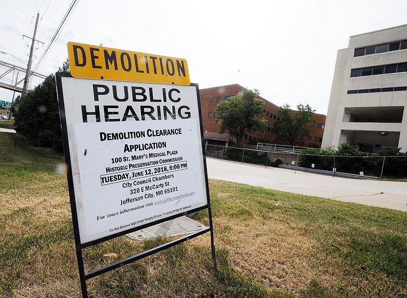 The old St. Mary's Hospital displays signage outside indicating a public hearing for demolition.