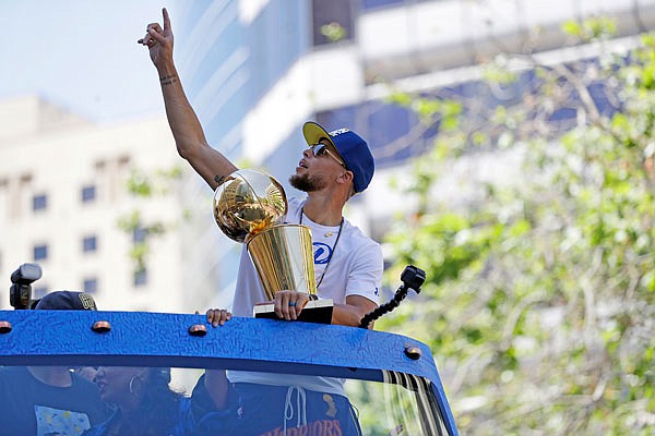 Stephen Curry of the Warriors carries the Larry O'Brien trophy during Tuesday's NBA championship parade in Oakland, Calif.