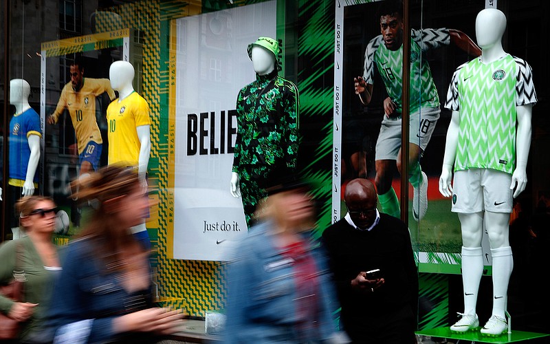 In this June 5, 2018 photo people walk by Nigerian and Brazil national soccer team jerseys which are on display at a shop in London. With just days to go before the FIFA World Cup, some winners and losers have emerged among the often wild and wacky team jerseys. (AP Photo/Frank Augstein)