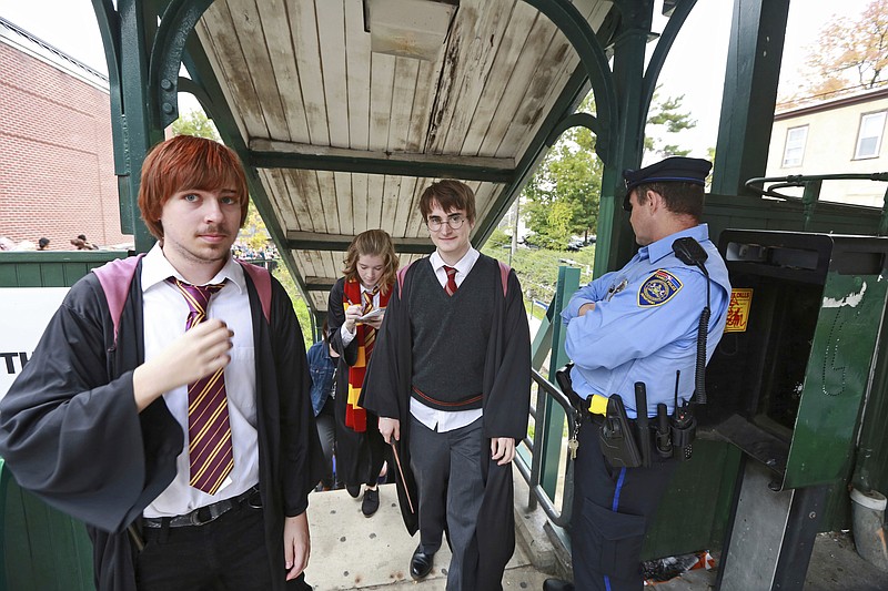 In this Oct. 18, 2014, photo, students from Chestnut Hill College in Philadelphia wear costumes to attend an annual festival based on the Harry Potter fantasy series conceived by British author J.K. Rowling, including Dan Lemoine, second from right, dressed as the title character; Mollie Durkin, second from left, dressed as the character Hermione Granger; and John Spiewak Jr., left, dressed as the character Ron Weasley, as they arrive at the festival in the Chestnut Hill neighborhood of Philadelphia. In 2018, Warner Bros. notified organizers of Harry Potter fan festivals around the U.S. of new guidelines prohibiting any use of names, places or objects from the fantasy series, in an effort to crack down on unauthorized commercial activity at such events. (David Swanson/The Philadelphia Inquirer via AP)