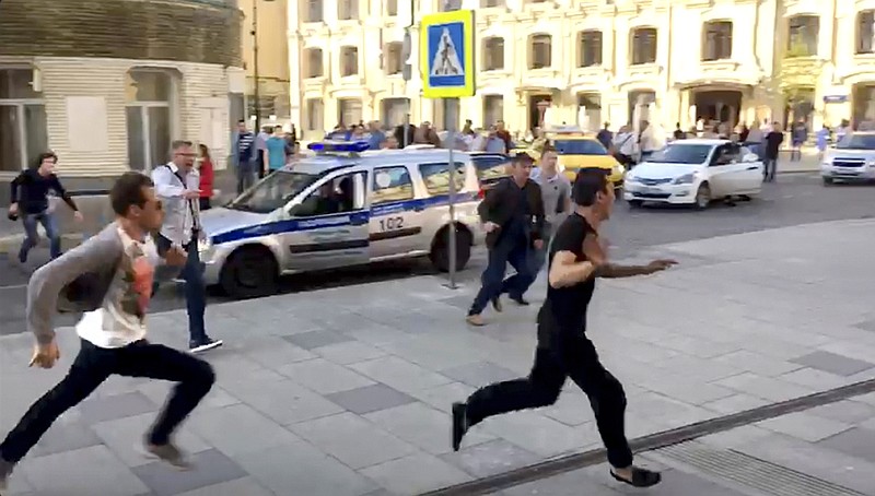 In this image taken from video provided by Viktoria Geranovich, a taxi driver, right, runs away from the scene after he crashed his taxi into pedestrians on a sidewalk near Red Square in Moscow, Russia, Saturday, June 16, 2018. Eight people, including two from Mexico, were injured in the crash. Video circulated on Russian social media and some news websites showed the taxi approaching a stopped line of cars, then veering onto the sidewalk and striking pedestrians. It then hit a traffic sign and bystanders tried to wrestle the driver out of the taxi, but he broke their grip and ran away; it was not clear how he was finally detained. (Viktoria Geranovich via AP)