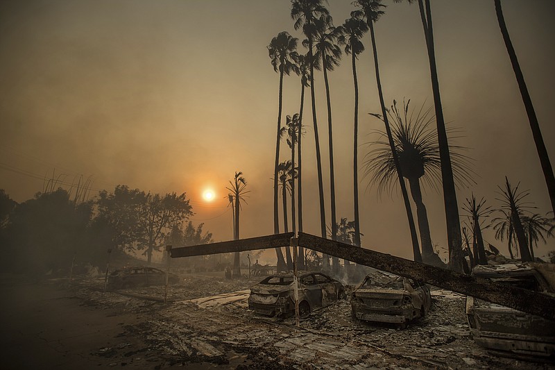 FILE - In this Dec. 5, 2017 file photo, smoke rises behind a destroyed apartment complex as a wildfire burns in Ventura, Calif. In the 30 years since 1988, the number of acres burned in the U.S. by wildfires has doubled. (AP Photo/Noah Berger, File)